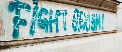 Close-Up eines Schriftzuges auf einer Hauswand, zu lesen ist "Fight Sexism" als Graffito