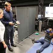 Professor Marc Latoschik und seine Mitarbeiterin Andrea Bartl (mit VR-Brille) erklären, wie Virtuelle Realität das Reha-Training nach einer Knie-Operation effektiver machen kann.